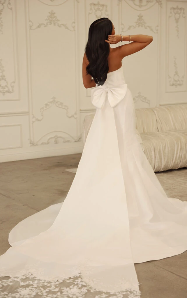 Bride wearing strapless wedding dress with fabric-covered buttons and bow train