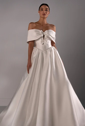 Bride wearing satin ballgown wedding dress with off-the-shoulder sleeves and bow details