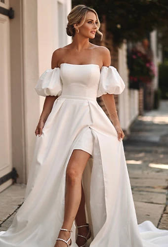 Bride wearing strapless wedding dress with overskirt, leg slit and puff sleeves