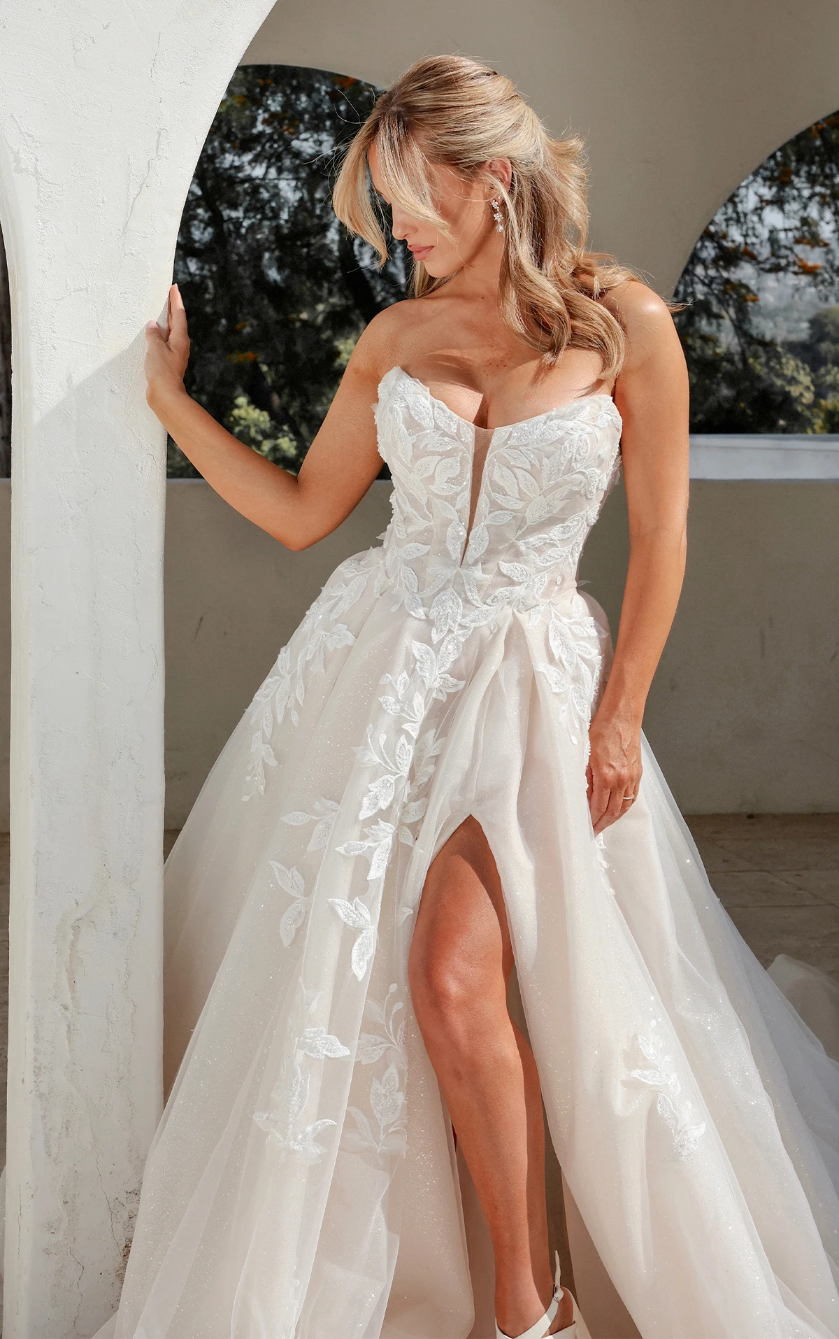 Bride wearing strapless floral lace wedding dress with leg slit.