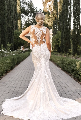 Bride wearing vintage lace wedding dress with floating fabric buttons and multi-layered train