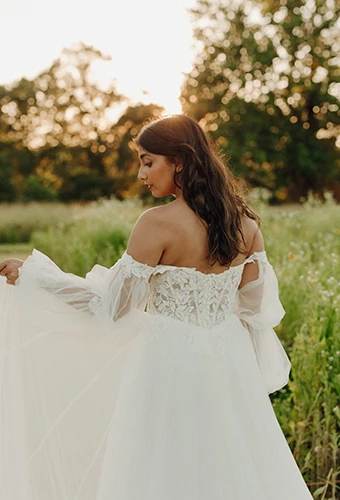 bride facing away lifting skirt of off the shoulder wedding dress - 7573 by Stella York