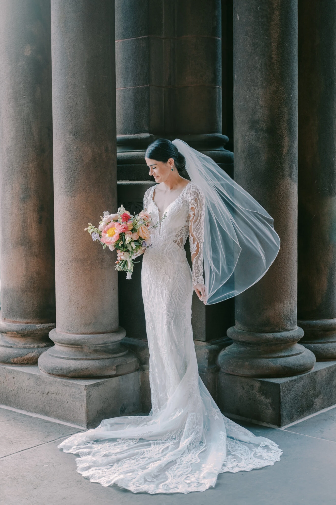 real bride erin posing in front of marble pillars with veil blowing in the wind - D3150 by Essense of Australia