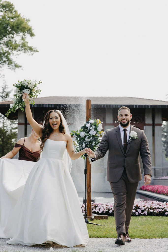 real bride olivia holding husbands hand walking down the aisle - style 7711 by Stella York