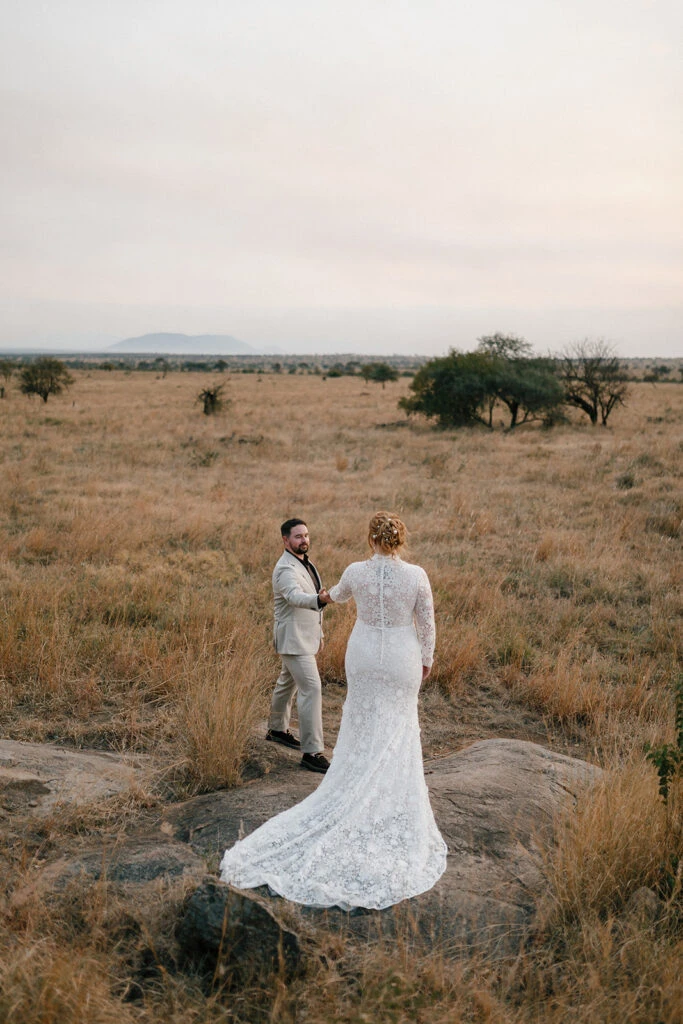 sophie and tom standing on rocks in the serengeti holding hands - layne by All Who Wander