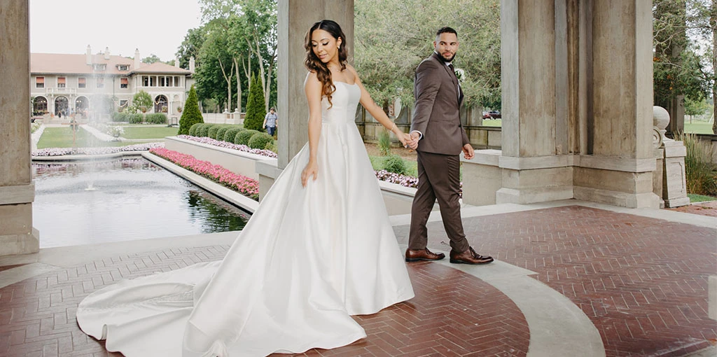 real bride olivia holding husbands hand in pavilion - style 7711 by Stella York