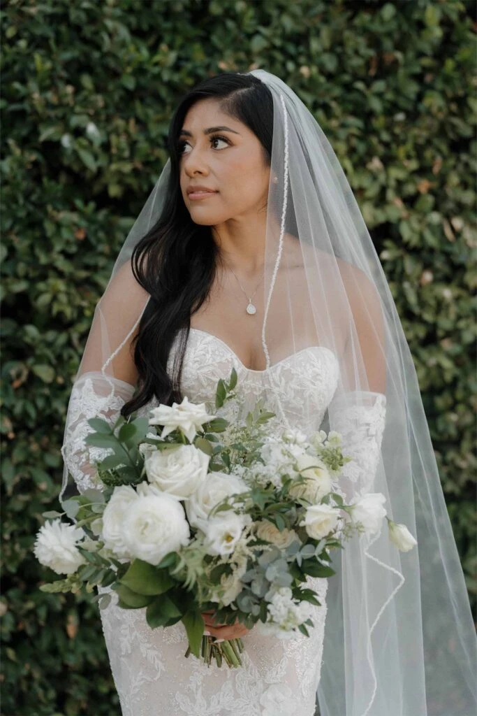 real bride angie posing with bouquet in front of greenery wearing 1367 by Martina Liana