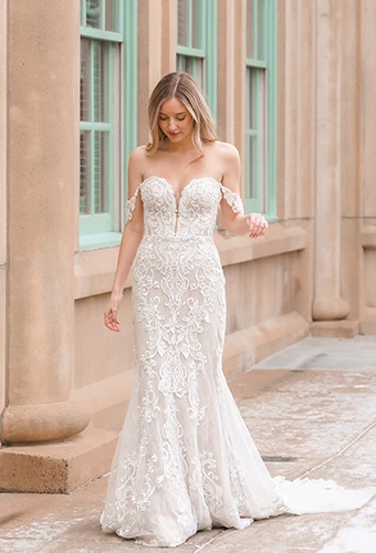 Bride wearing vintage-inspired lace wedding dress with drapey off-the-shoulder straps and plunge sweetheart neckline