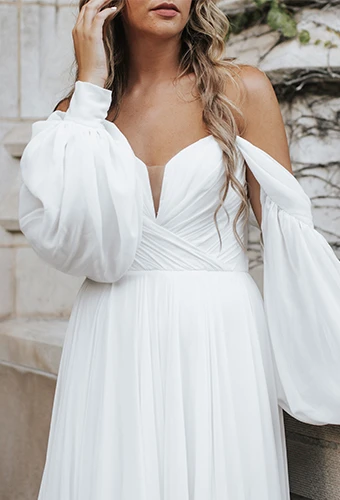 bride touching hair wearing chiffon off the shoulder wedding dress