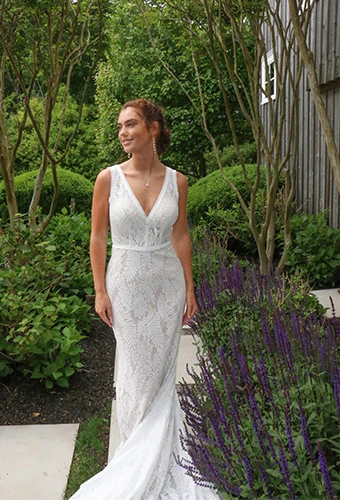 model wearing all-over lace wedding dress in a green garden - kalani by all who wander