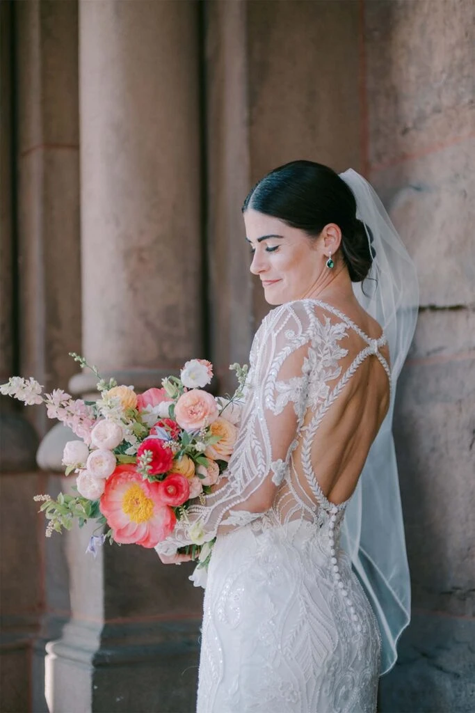 real bride erin posing with bouquet in front of marble pillars wearing D3150 by Essense of Australia