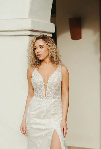 bride leaning against a stucco pillar wearing Stella York style 8157
