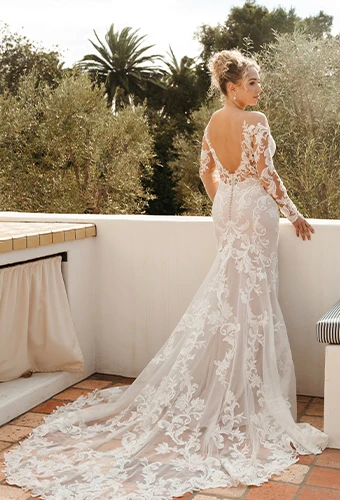 Bride wearing lace fit and flare wedding dress with long sleeves and low back