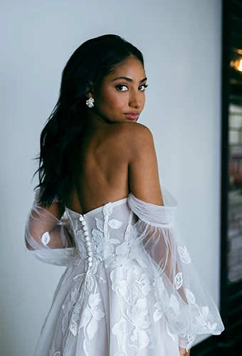 bride posing over the shoulder wearing lace off-the-shoulder wedding dress - d4029 by Essense of Australia