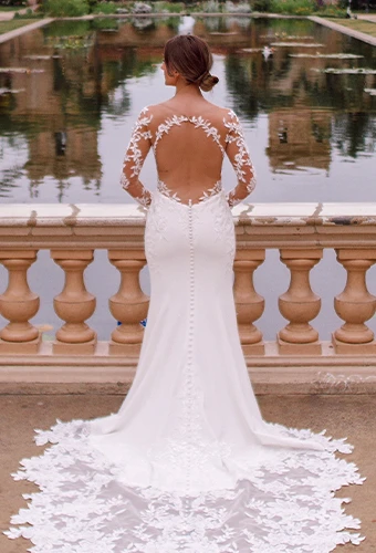 Bride wearing long sleeve illusion lace wedding dress with keyhole open back and fabric-covered buttons