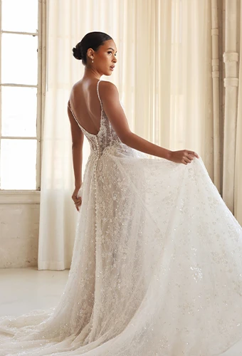 Bride wearing sparkling lace wedding dress with sheer sides and plunging v back