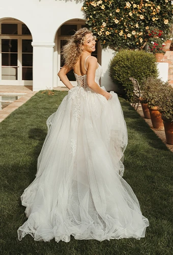 Bride wearing lace wedding dress with spaghetti straps in backyard