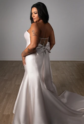Plus size bride wearing strapless wedding dress with bow back detail