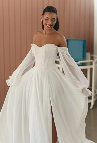 Bride wearing chiffon wedding dress with off the shoulder long sleeves and high leg slit