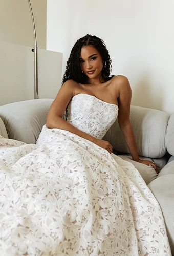 Bride wearing strapless lace wedding dress lounging on a couch