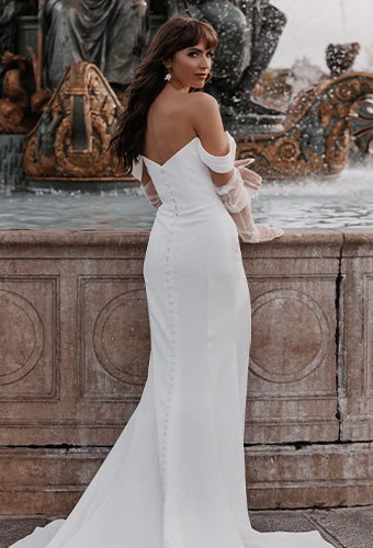 Bride wearing sheath wedding dress with cowl neckline and off-the-shoulder straps