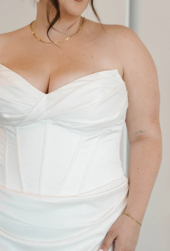 Plus size bride wearing strapless sheath wedding dress with sweetheart neckline and boning