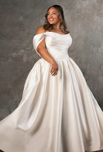 Plus-size bride wearing ballgown wedding dress with off-the-shoulder straps and lace neckline detail