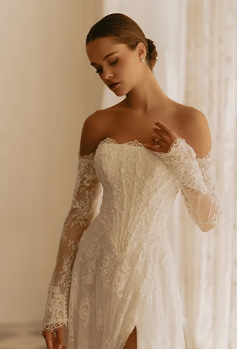 Bride wearing strapless lace wedding dress with straight across neckline, optional sleeves and high leg slit