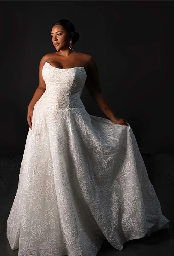 Plus size bride wearing lace wedding dress with strapless scoop neckline and drop waist