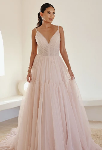Bride wearing simple tulle wedding dress in blush pink with v-neckline and thin spaghetti straps