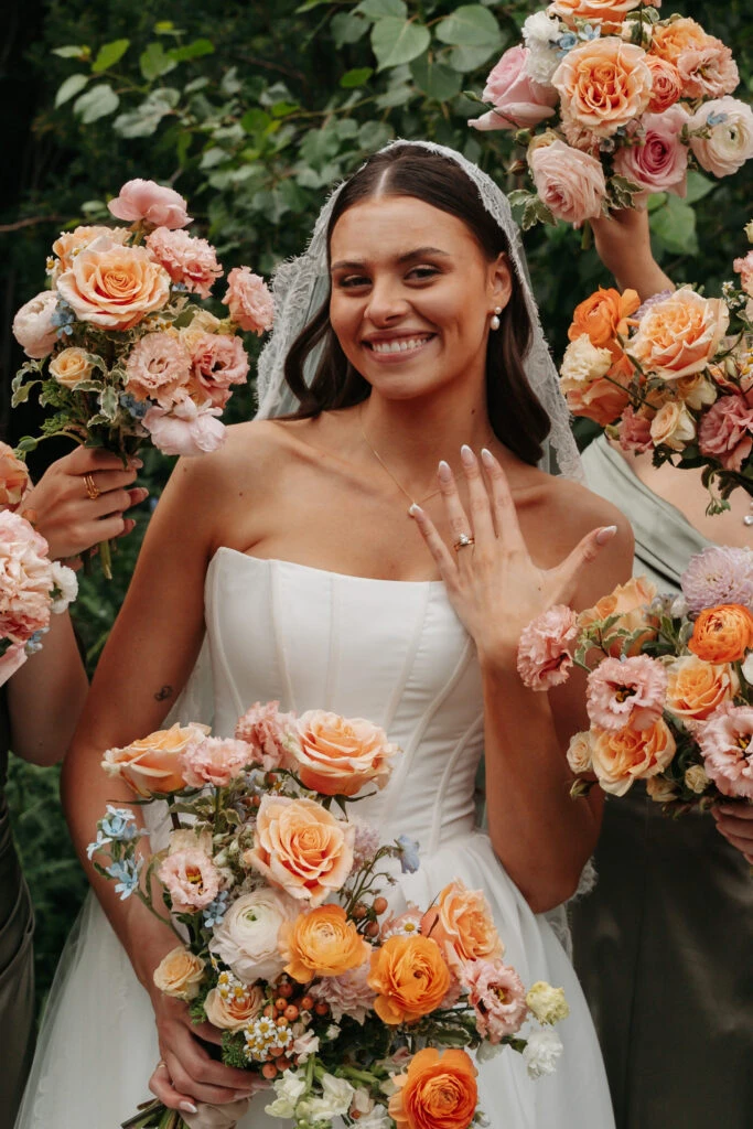 Real bride Gabby posing in her wedding gown with bouquets of flowers