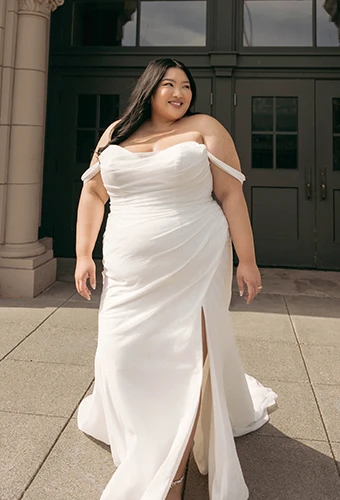 Plus size bride wearing simple sparkling tulle wedding dress with high leg slit, off-the-shoulder straps and sweetheart neckline