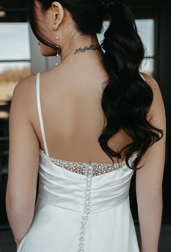 Bride wearing simple sheath wedding dress with spaghetti straps and pearl details
