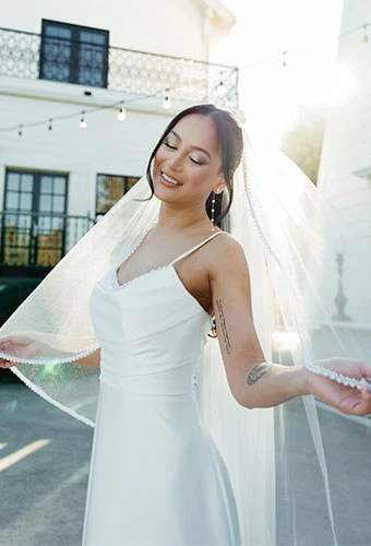 Bride wearing simple sheath wedding dress with spaghetti straps and pearl details