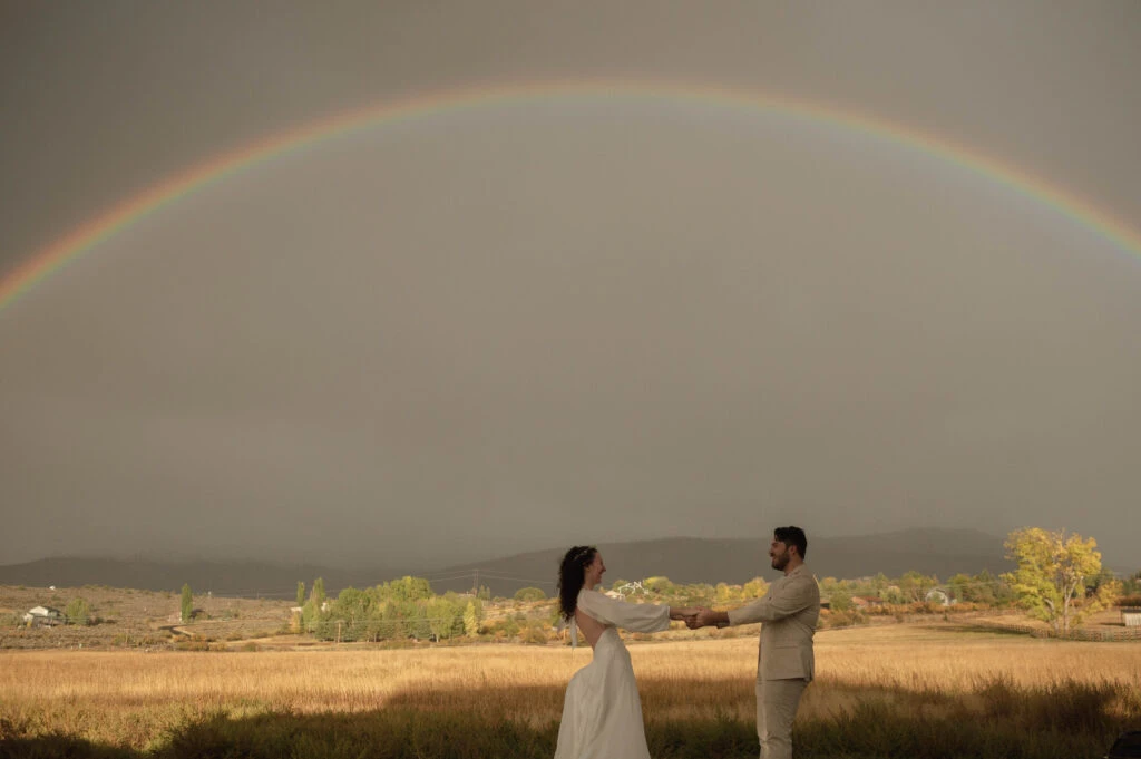 Real bride Hayley posing with her husband in front  of a rainbow