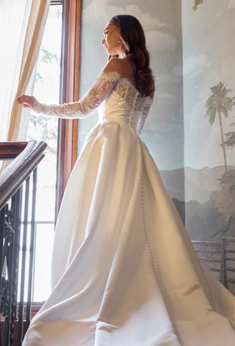 Bride wearing sating wedding dress with lace off-the-shoulder sleeves