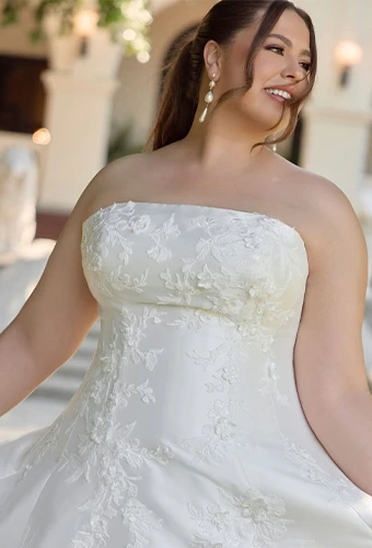 Plus size bride wearing strapless satin wedding dress with lace appliques