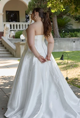 Plus size bride wearing strapless satin wedding dress with lace appliques