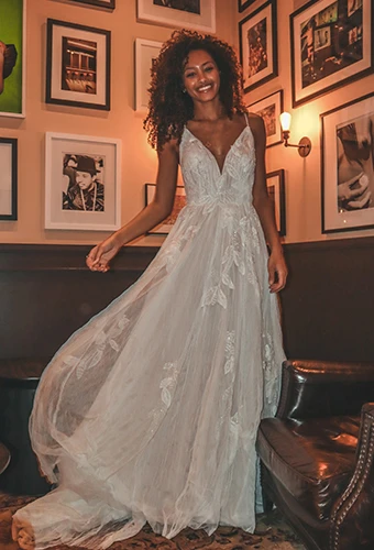 Bride wearing boho tulle wedding dress with v-neckline, lace details and thin spaghetti straps