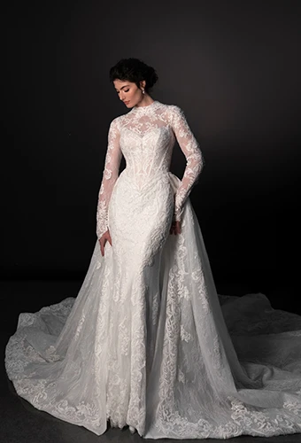 Bride wearing lace fit and flare wedding dress with long sleeves and detachable overskirt