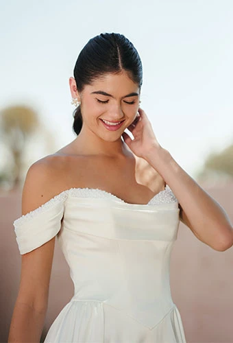 Bride wearing satin a-line wedding dress with pearl neckline and off-the-shoulder straps