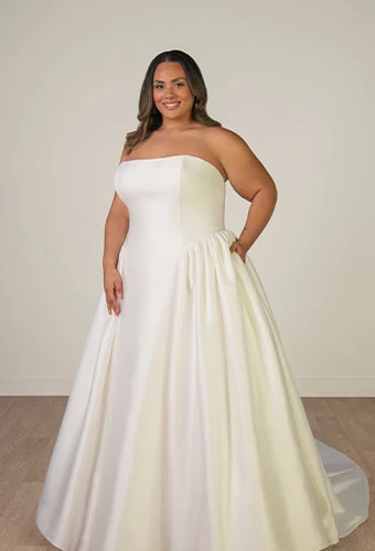 Plus size bride wearing strapless a-line wedding dress with straight across neckline and pockets