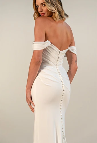 Bride wearing simple crepe wedding dress with off-the-shoulder straps and fabric covered buttons