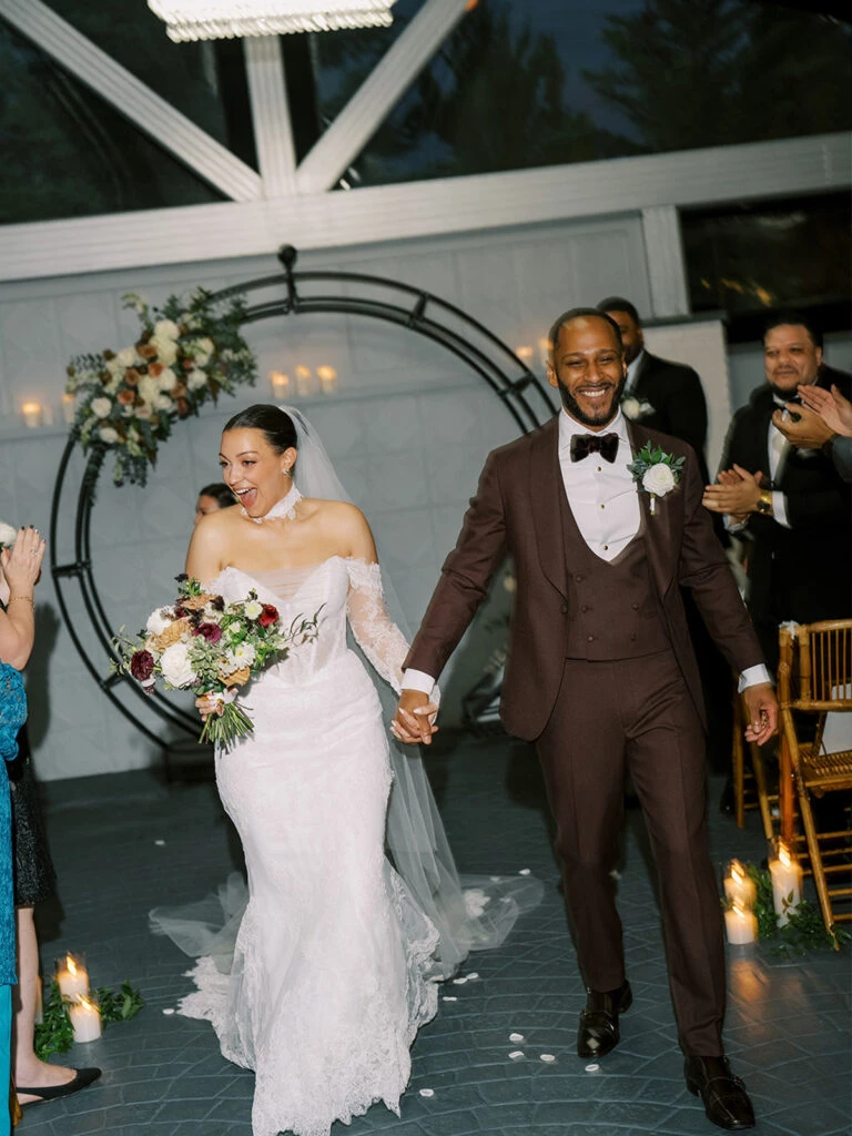 Real bride Alexa posing with her husband walking down the aisle
