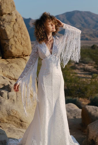 Bride wearing lace wedding dress with long sleeves and fringe.