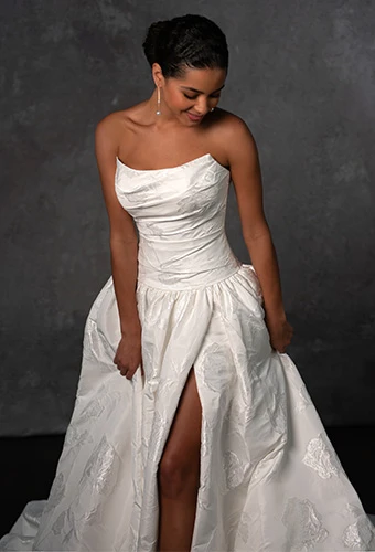 Bride wearing strapless ballgown wedding dress with scoop neckline, drop waist and high leg slit