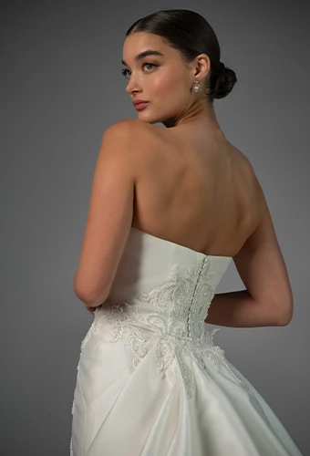 Bride waring strapless lace wedding dress with straight across neckline and overskirt