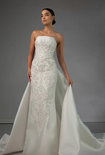Bride waring strapless lace wedding dress with straight across neckline and overskirt