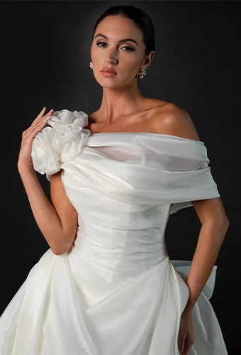 Bride wearing a-line wedding dress with asymmetrical one shoulder and floral accent