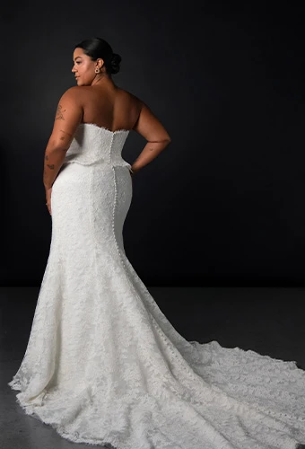 Plus size bride wearing lace strapless fit-and-flare wedding dress with peplum waist